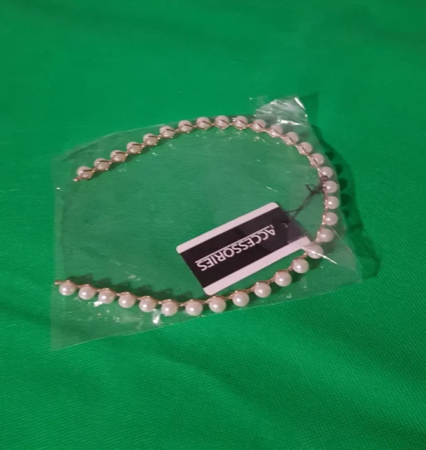 Hair band with white beads on golden metal.